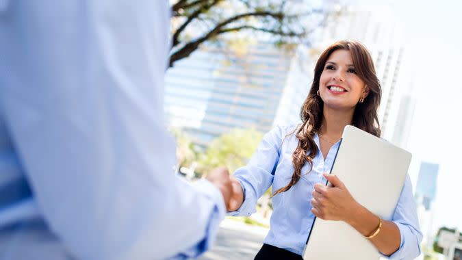 Business woman shaking hands with a client - outdoors.