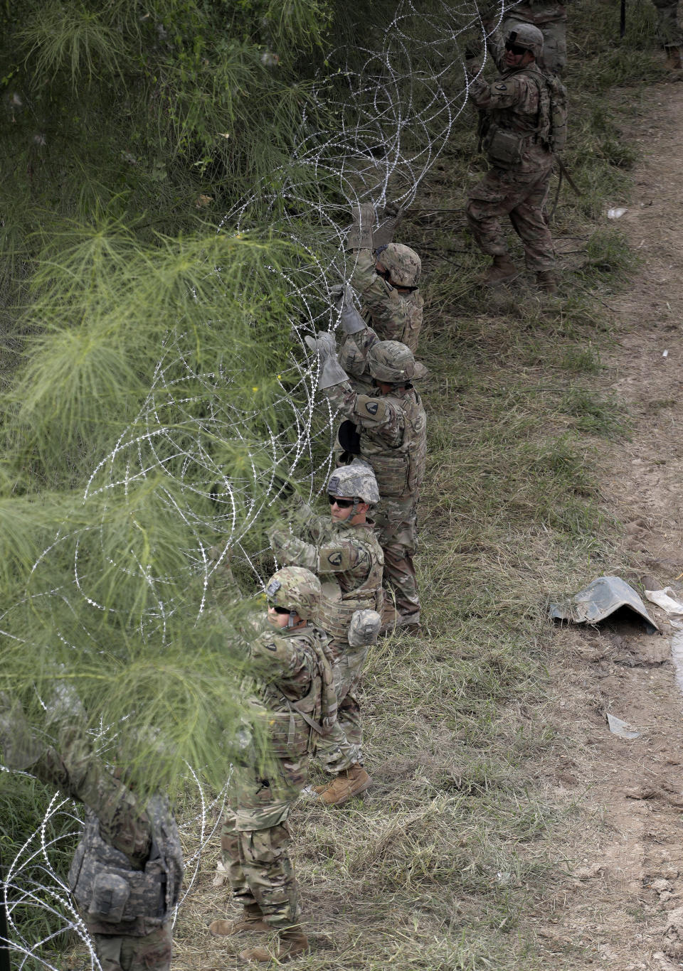 Members of the U.S. military place razor wire along the U.S.-Mexico border near the McAllen-Hidalgo International Bridge, Friday, Nov. 2, 2018, in McAllen, Texas. (AP Photo/Eric Gay)