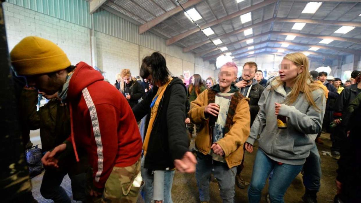 People dance during a wild party in a disused hangar in Lieuron about 40km (around 24 miles) on south of Rennes, on January 1, 2021. - A wild party that began on December 31 evening in Lieuron, still gathered on January 1 around 2,500 participants  