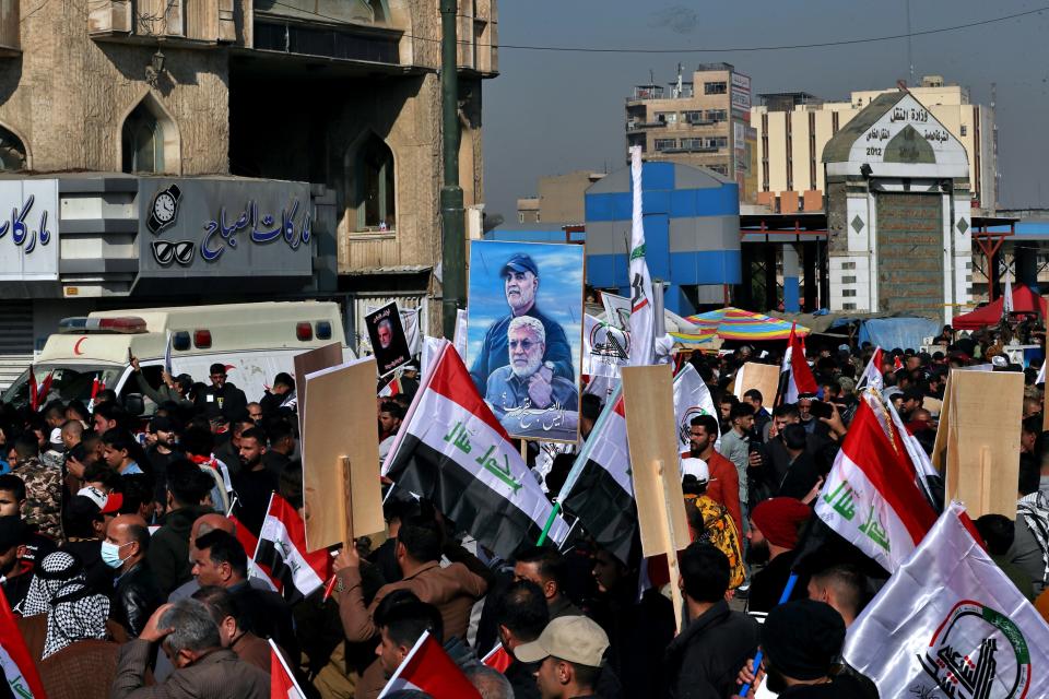 Supporters of the Popular Mobilization Forces hold a poster of Abu Mahdi al-Muhandis, deputy commander of the Popular Mobilization Forces, front, and General Qassem Soleimani, head of Iran's Quds force during a protest, in Tahrir Square, Iraq, Sunday, Jan. 3, 2021. Thousands of Iraqis converged on a landmark central square in Baghdad on Sunday to commemorate the anniversary of the killing of Soleimanil and al-Muhandis in a U.S. drone strike. (AP Photo/Khalid Moha