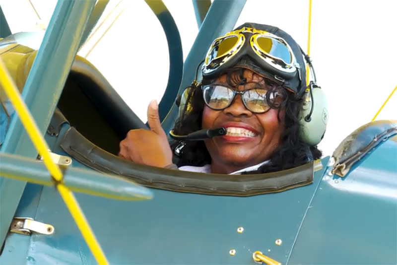 Gigi Coleman gestures as she prepares to take a flight in EAA’s 1929 TravelAir biplane at the EAA Aviation Museum’s Pioneer Airport in Oshkosh, Wis., in June 2021. (Courtesy EAA Museum)