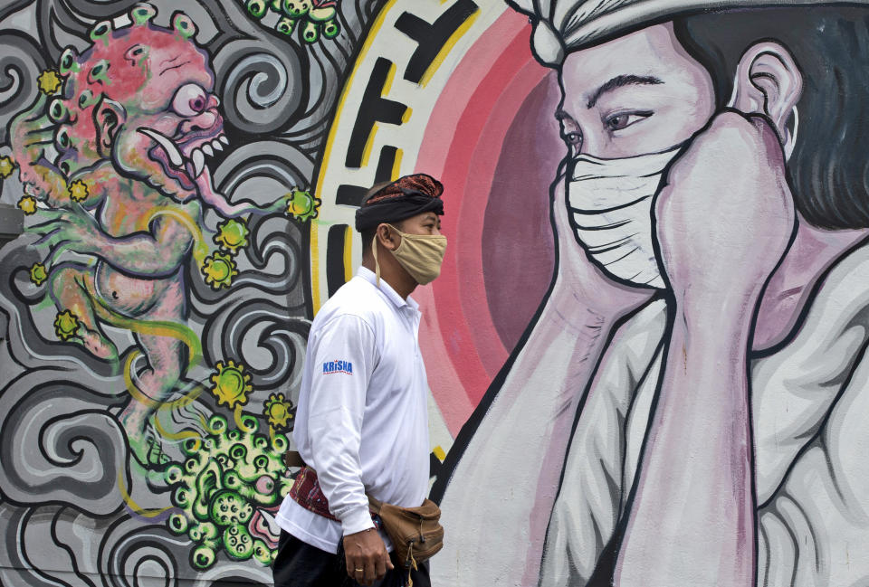 A man walks past a coronavirus-themed mural in Denpasar, Bali, Indonesia, Tuesday, Jan. 26, 2021. Indonesia has reported more cases of the virus than any other countries in Southeast Asia. (AP Photo/Firdia Lisnawati)