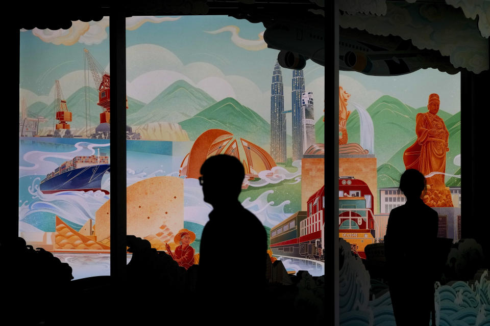 Attendees are silhouetted as they pass by an art display depicting China's Belt and Road Initiative at the China National Convention Center in Beijing, Wednesday, Oct. 18, 2023. (AP Photo/Andy Wong)