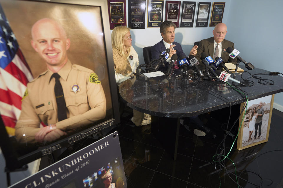 Attorney Bradley Gage, middle, and Kim Clinkunbroomer, left, and Mike Clinkunbroomer, the parents of late Los Angeles Sheriff's Deputy Ryan Clinkunbroomer, pictured left, announce the precursor of a lawsuit against the Sheriff's Department at a news conference in Los Angeles on Tuesday, Nov. 28, 2023. Los Angeles County Sheriff's Deputy Clinkunbroomer was shot and killed Sept. 16, 2023, while sitting in his patrol car in Palmdale, Calif. His parents are seeking justice for their son and looking to make a change in LACSD's policies to protect other deputies from death. (AP Photo/Damian Dovarganes)