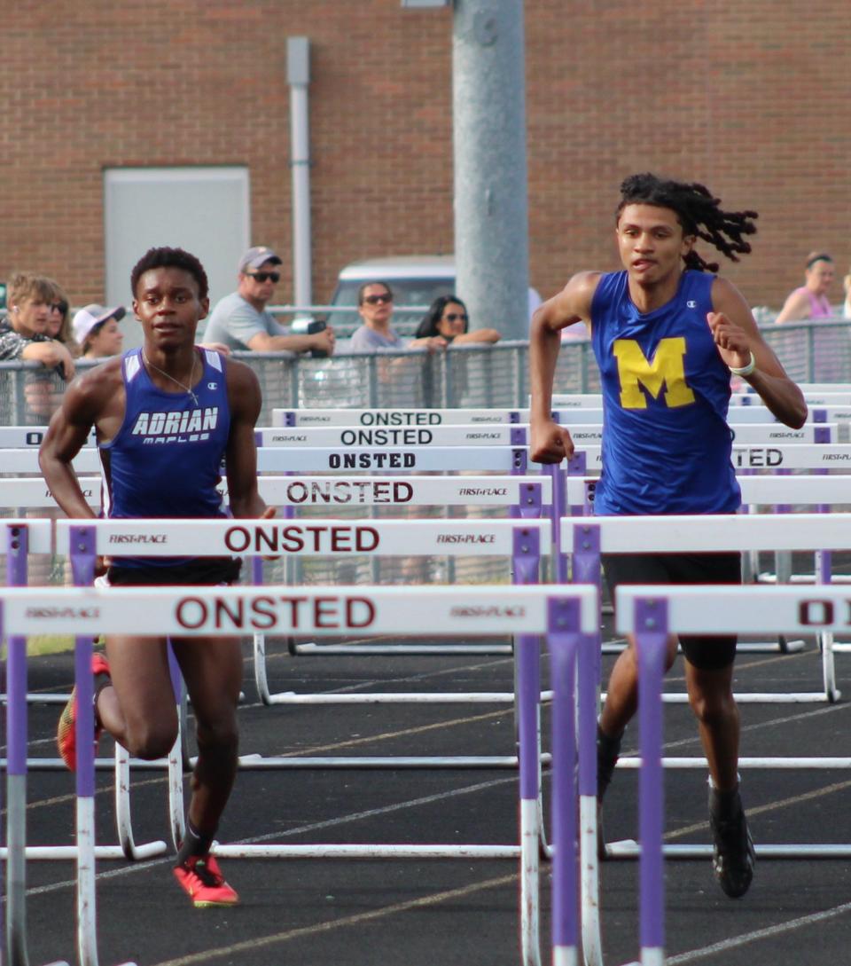 Adrian's Isaiah Fox (left) and Madison's Michael Benson compete in the high hurdles event at the Lenawee County Track and Field Championships at Onsted.