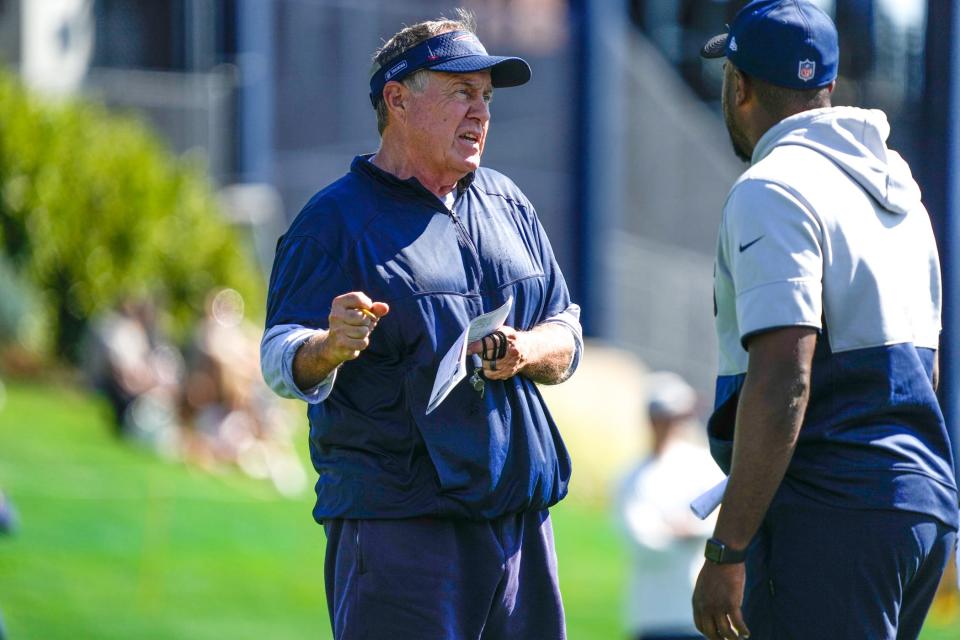 Patriots coach Bill Belichick spends time with the receivers during early drills.