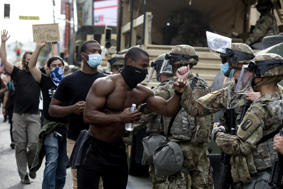 Manifestantes saludan a miembros de la Guardia Nacional mientras marchan por el Bulevar de Hollywood, el martes 2 de junio de 2020 en la sección de Hollywood de Los Ángeles, California, durante una protesta por la muerte de George Floyd, fallecido el 25 de mayo tras ser reducido por la policía de Minneapolis. (AP Foto/Ringo H.W. Chiu)