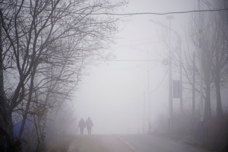 Rescue workers walk on a road leading to the Hushan gold mine where workers are trapped underground after an explosion, in Qixia