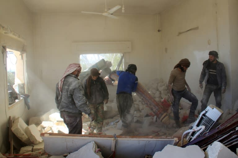 Syrian civil defence members and civilians inspect the house of nine-year-old Syrian Abdel Basset Al-Satuf after heavy air strikes the previous day