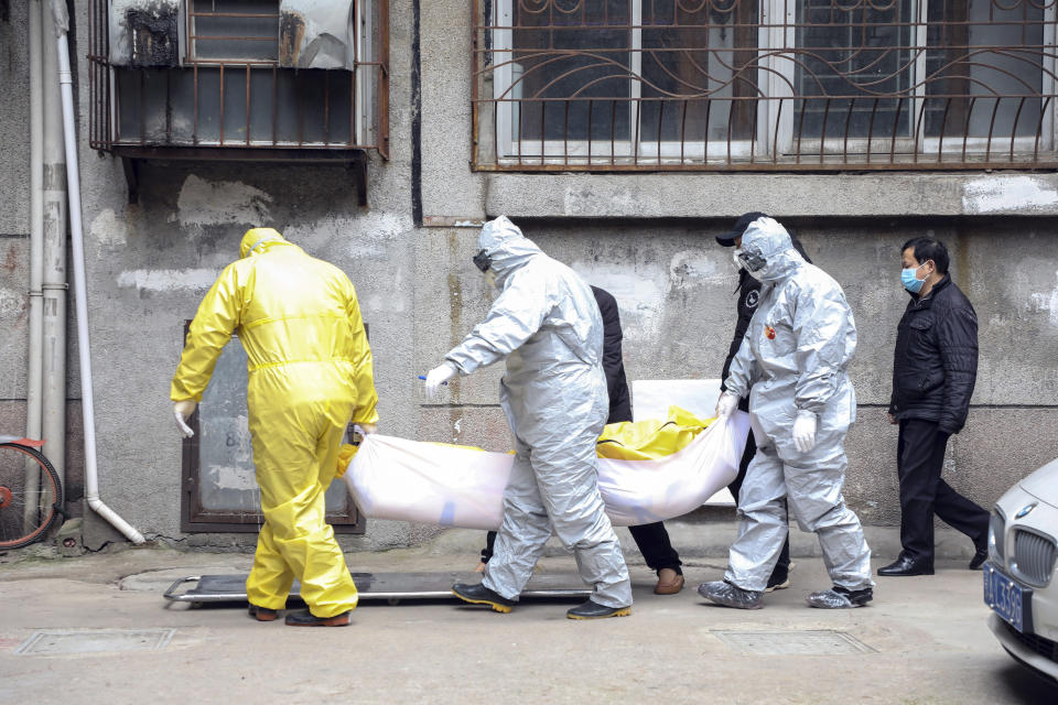 In this Feb. 1, 2020, photo, funeral home workers remove the body of a person suspect to have died from a virus outbreak from a residential building in Wuhan in central China's Hubei Province. The Philippines on Sunday reported the first death from a new virus outside of China, where authorities delayed the opening of schools in the worst-hit province and tightened quarantine measures in a city that allow only one family member to venture out to buy supplies. (Chinatopix via AP)