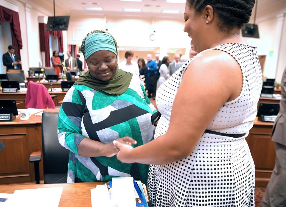 At-Large Council Member Zulfat Suara, left, is greeted by Council Member Delishia Danielle Porterfield before the new council’s first meeting at city hall on Tuesday, Oct. 1, 2019.