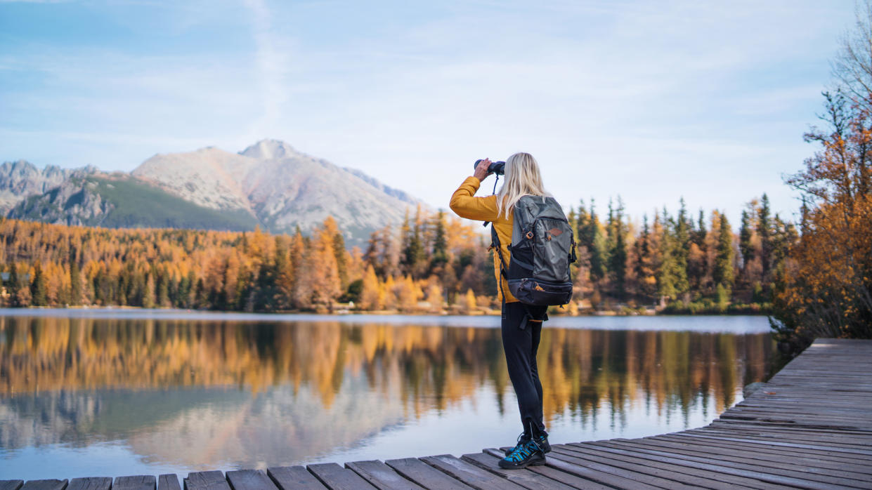  How do binoculars work: hiker using binoculars. 