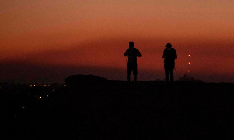 Hikers in LA’s Griffith Park look west where a layer of smoke from the Saddleridge Fire hangs in the sky.
