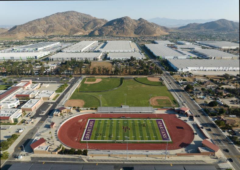 FONTANA, CA - JULY 25: In a view looking south, Jurupa Hills High School sits among warehouses. The Fontana City Council is considering a developer's bid to build three more warehouses in the dirt lots just south of Jurupa Hills High School. Currently, there are more than 20 warehouses already located within a mile of the school. Photographed on Tuesday, July 25, 2023 in Fontana, CA. (Myung J. Chun / Los Angeles Times)