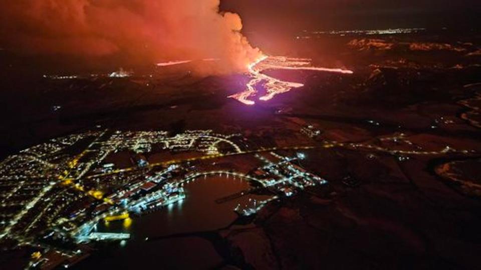 Nachts fließt ein Fluss aus leuchtend rotem Feuer neben den Lichtern der Stadt