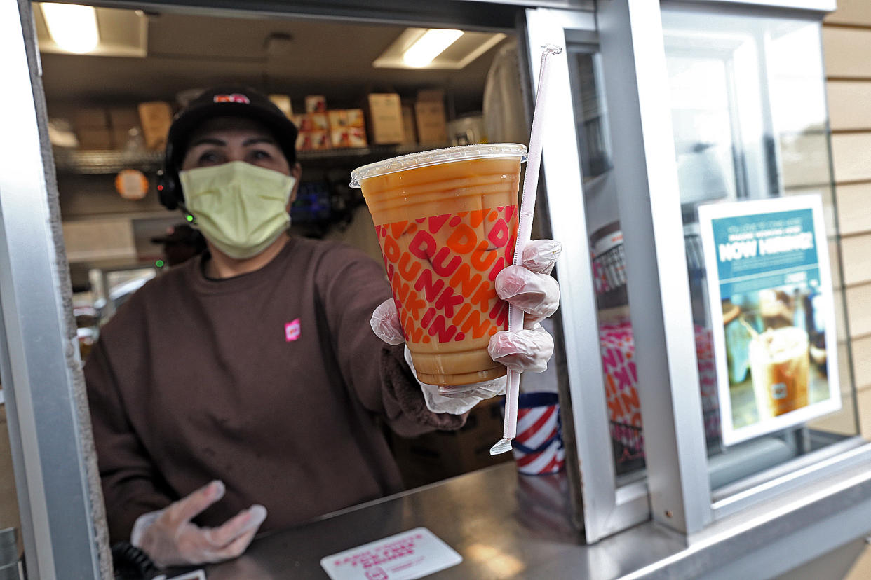NORWELL, MA. - MARCH 17:  A Dunkin' worker hands a coffee out of a drive-thru window wearing gloves and a mask as the Coronavirus continues to spread on March 17, 2020 in Norwell, Massachusetts. (Staff Photo By Matt Stone/MediaNews Group/Boston Herald)