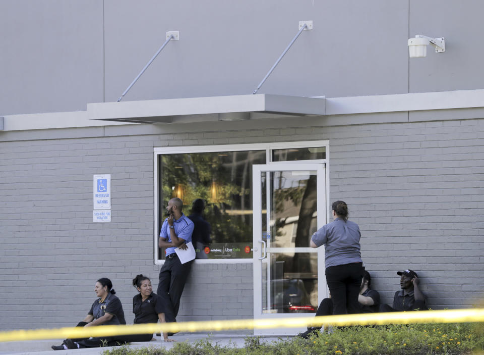 Employees of the McDonald's, located on Lasalle Street near the shooting, sit outside the closed restaurant in Mandeville, La., Friday, Sept. 20, 2019. One police officer was fatally shot and another wounded Friday after a vehicle chase north of New Orleans. (David Grunfeld/The Advocate via AP)