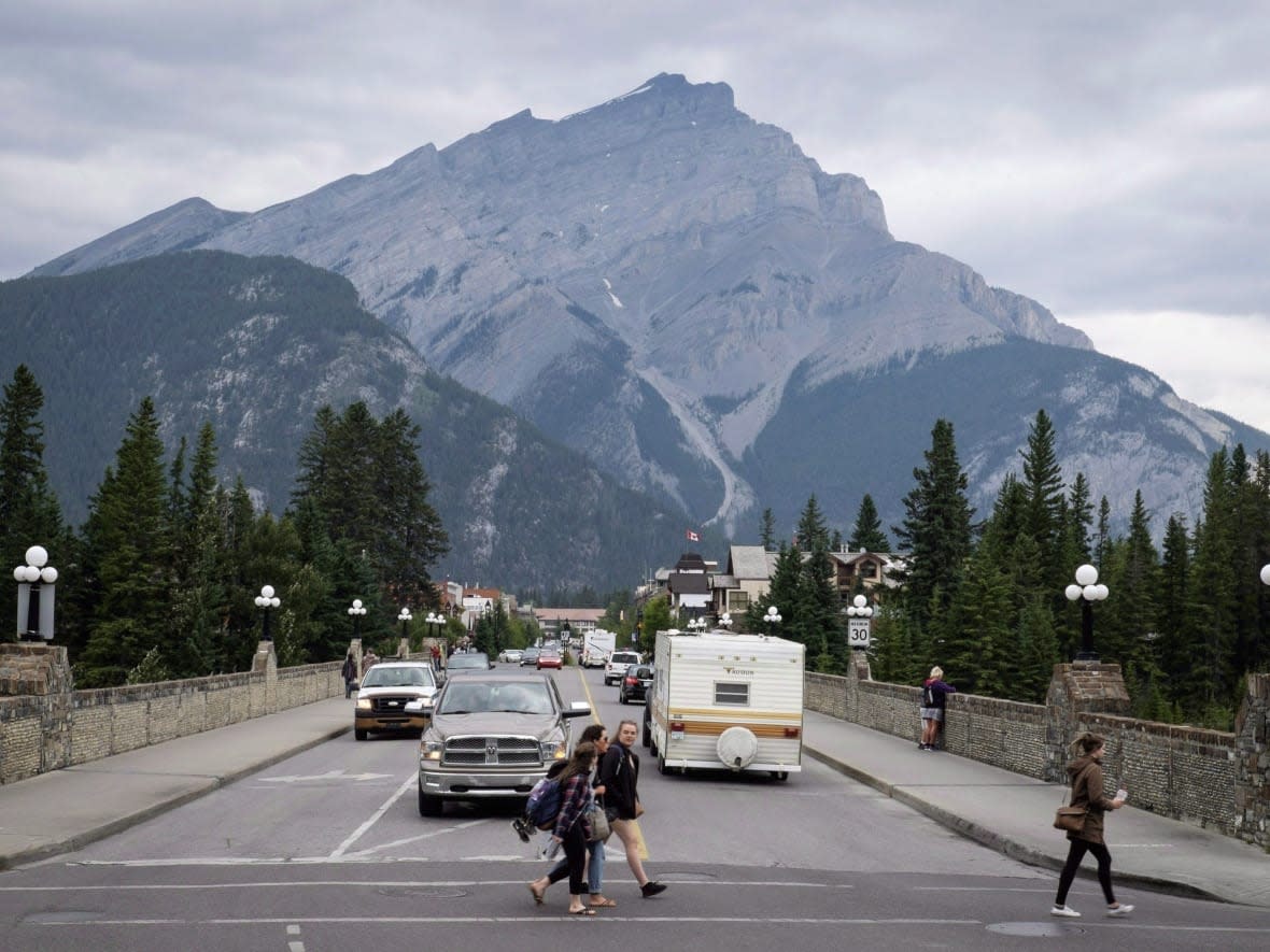 Pedestrians cross the street in Banff in Banff National Park on July 21, 2017.  (Jeff McIntosh/The Canadian Press - image credit)