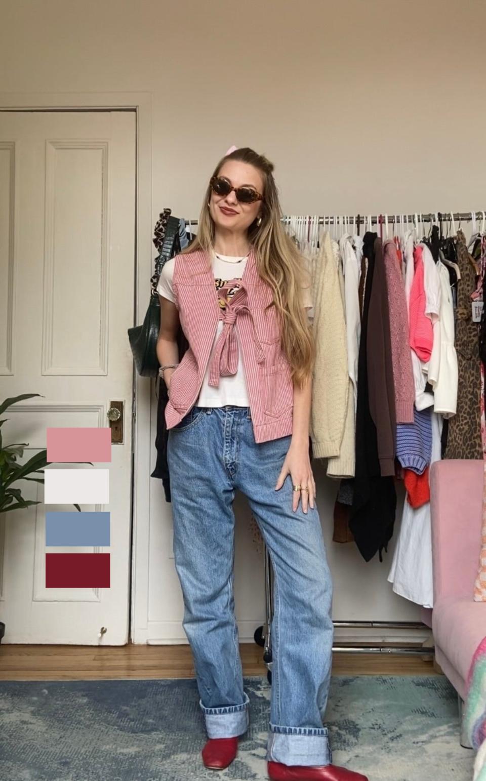 Woman in casual attire with vest and jeans, accessorized with a headband and sunglasses, standing in a room with a clothing rack