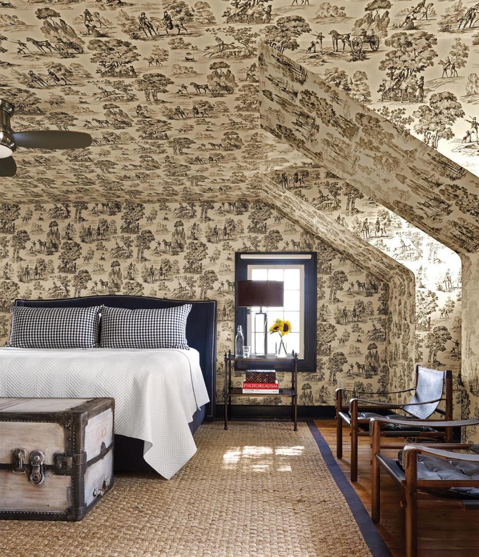 bedroom with toile covered walls and ceiling as well as a vintage trunk at the foot of the bed