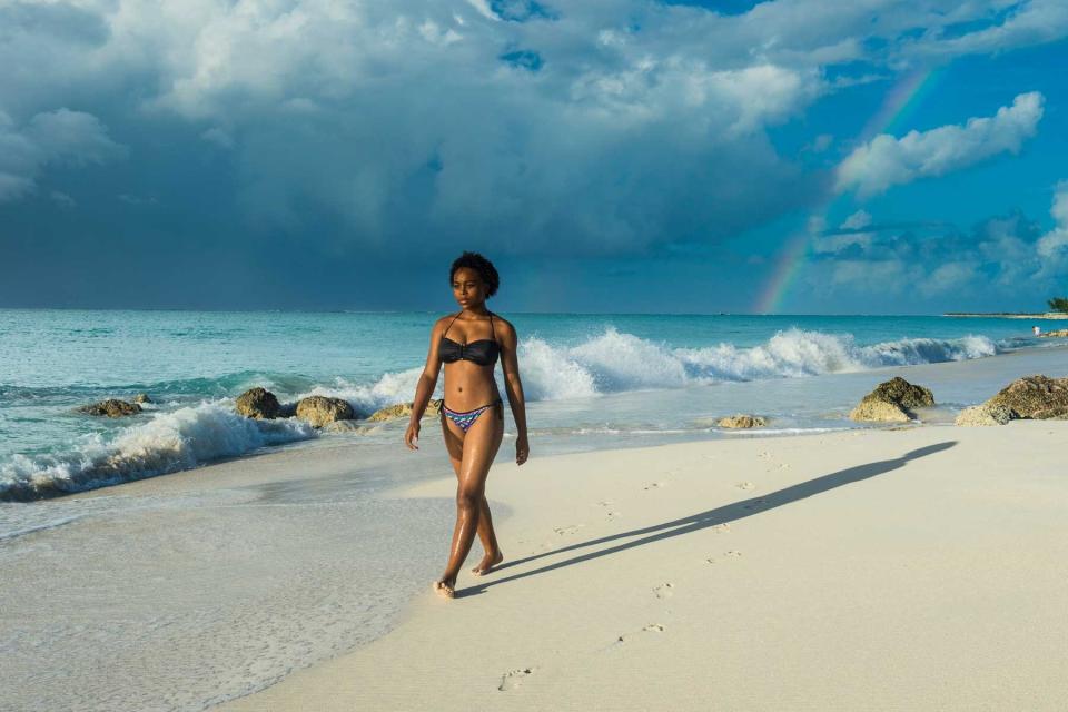 Woman wearing bikini walking at Grace Bay beach against cloudy sky, Providenciales, Turks And Caicos Islands