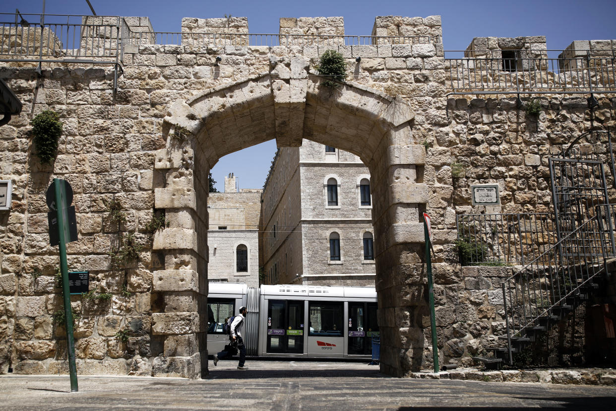 A man runs as Jerusalem's light rail passes by at New Gate in Jerusalem's Old City. (Photo: Nir Elias/Reuters)