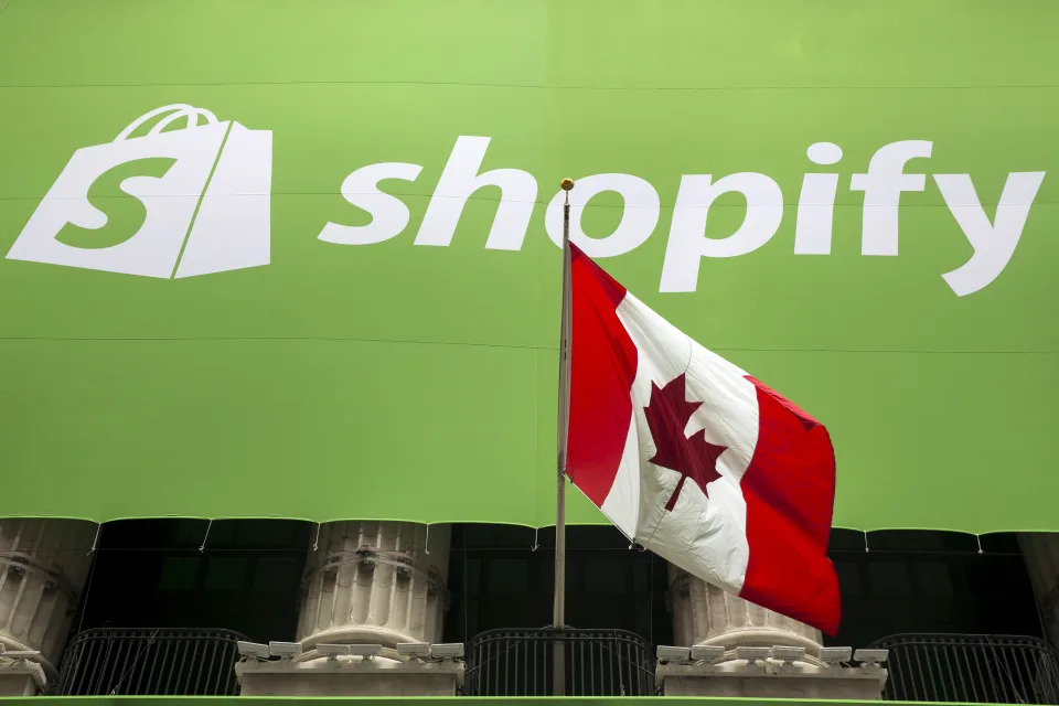 The logo of Shopify hangs behind the Canadian flag after the company's IPO at the New York Stock Exchange May 21, 2015. Picture taken May 21, 2015. REUTERS/Lucas Jackson