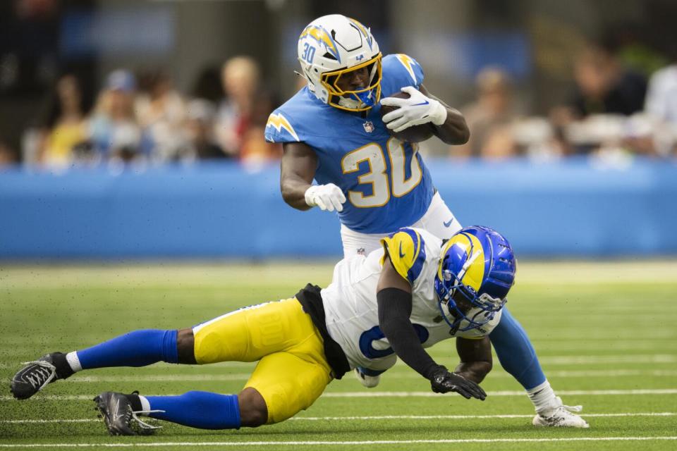 Chargers running back Kimani Vidal (top) tries to avoid a tackle from Rams defensive back Tre Tomlinson on Saturday.