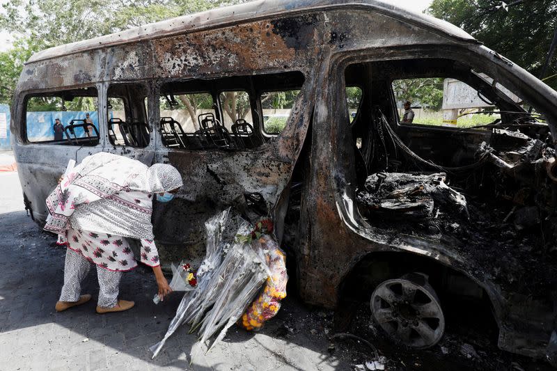 A student lays a bouquet in memory of her Chinese teachers, near the wreckage of a passenger van after a blast, during what they call a peaceful protest, outside the Confucius Institute at University of Karachi