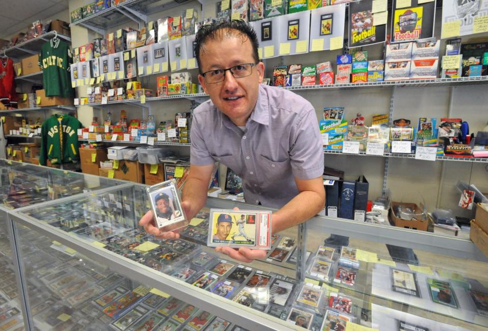 George Pepdjonovic holds baseball cards featuring Ken Griffey Jr., left, and Ted Williams at his George Pep's Baseball Card Shop in Quincy on Friday, April 30, 2021.