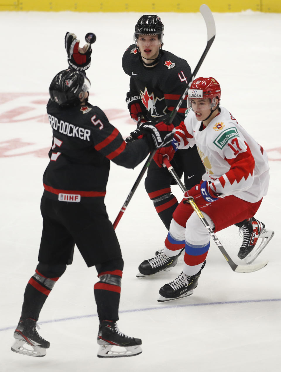 Canada's Jacob Bernard-Docker, left, catches the puck as Russia's Maxim Sorkin, right, and Canada's Bowen Byram skate by during the U20 Ice Hockey Worlds gold medal match between Canada and Russia in Ostrava, Czech Republic, Sunday, Jan. 5, 2020. (AP Photo/Petr David Josek)