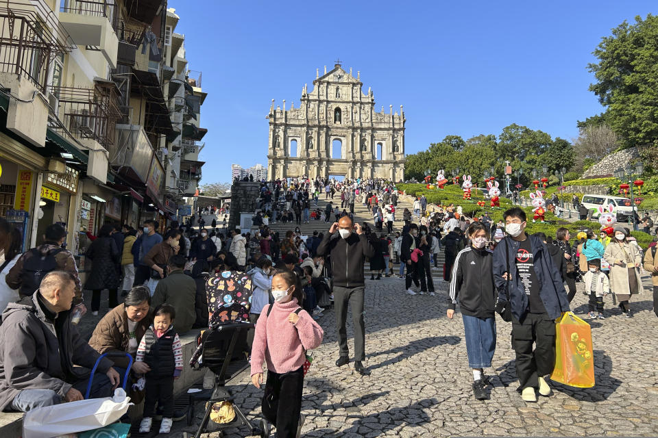 Travelers from mainland China gather near the Ruins of St. Paul's, a tourist destination in Macao, Wednesday, Jan. 18, 2022. A hoped for boom in Chinese tourism over next week's Lunar New Year holidays looks set to be more of a blip as most travelers avoid traveling overseas, if at all. (AP Photo/Kanis Leung)