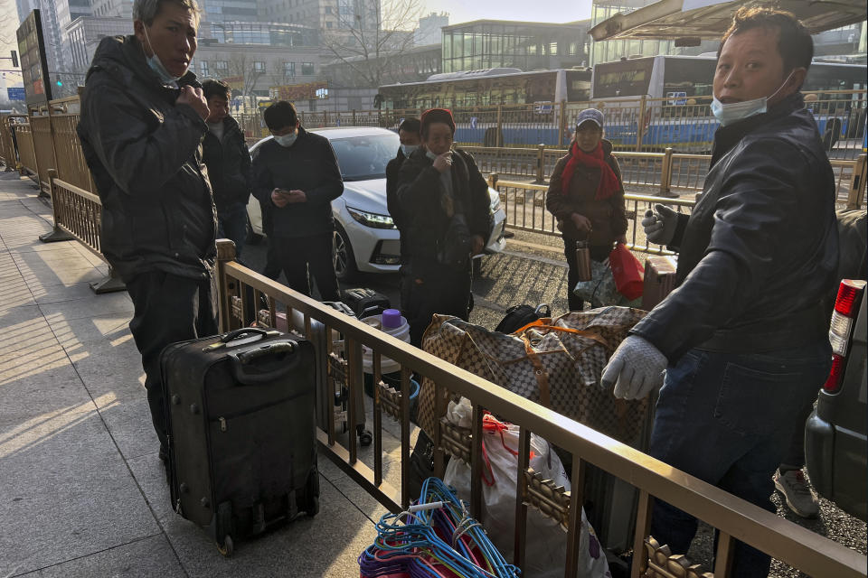 Migrant workers with their luggage take a break outside the West Railway Station before catching their trains in Beijing, Friday, Jan. 6, 2023. China is seeking to minimize the possibility of a major new COVID-19 outbreak during this month's Lunar New Year travel rush following the end of most pandemic containment measures. (AP Photo/Wayne Zhang)