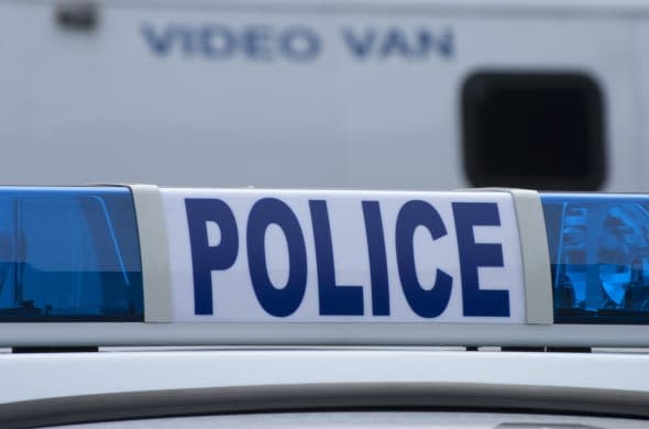 Closeup of police car sign with video unit vehicle in background.