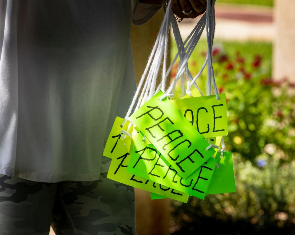 Volunteers hand out PEACE signs for people to wear before Tuesday's news conference and vigil at Fort Blount Park In Bartow.