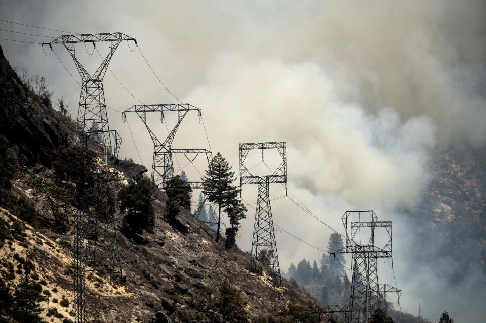 Smoke billows behind power lines as the Dixie Fire burns along Highway 70 in Plumas National Forest, Calif., on Friday, July 16, 2021. (AP Photo/Noah Berger)