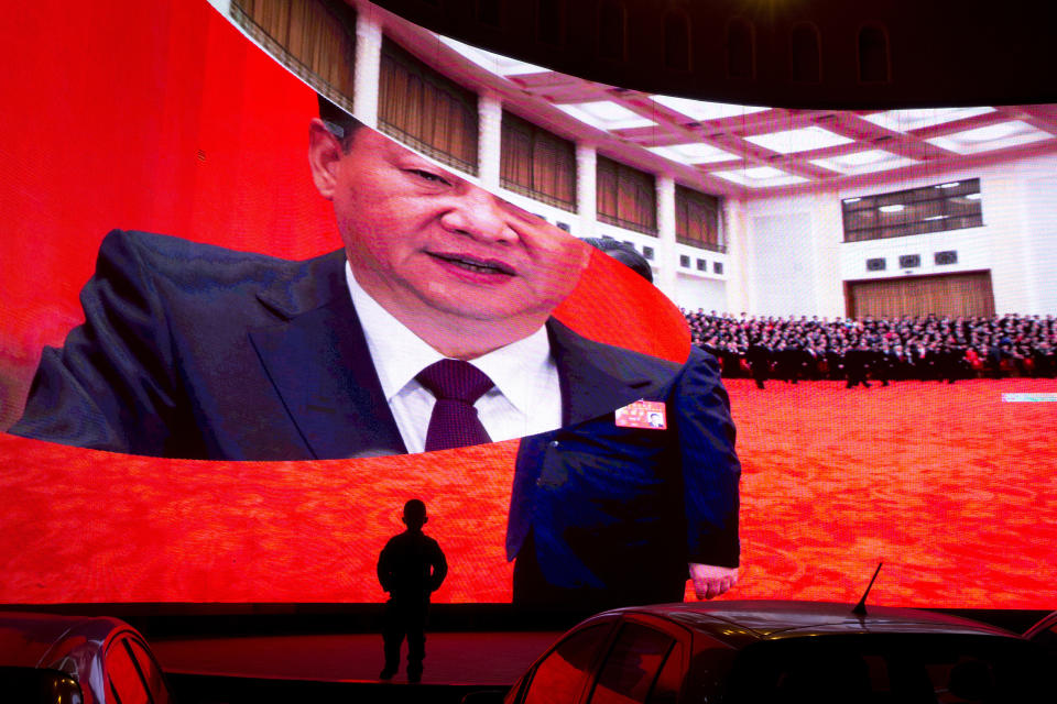 FILE - A child stands near a large screen showing photos of Chinese President Xi Jinping near a car park in Kashgar in western China's Xinjiang region on Dec. 3, 2018. Within China, the Communist Party under Xi has increased surveillance, tightened already strict control over speech and media and cracked down further on dissent, censoring even mildly critical views and jailing those it believes went too far. Authorities have repressed predominantly Muslim groups in China's Xinjiang region in a harsh anti-extremism campaign that has raised a human rights outcry internationally. (AP Photo/Ng Han Guan, File)