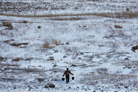 A North Korean man is photographed from the Chinese side of the border south of Changbai in China as he carries buckets of water from the frozen Yalu River, south of Hyesan in North Korea, November 22, 2017. REUTERS/Damir Sagolj