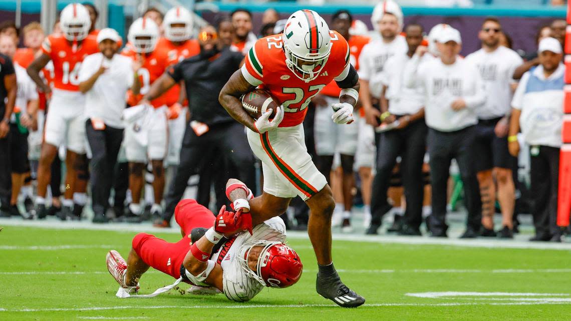 Miami Hurricanes running back Mark Fletcher Jr. (22) breaks a tackle by Louisville Cardinals defensive back Cam’Ron Kelly (11) to score in the first quarter on Saturday, November 18, 2023.