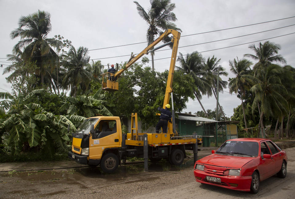 An electric company worker remove tree branches felled on power lines in the wake of Hurricane Ian in Havana, Cuba, Wednesday, Sept. 28, 2022. Cuba remained in the dark early Wednesday after Ian knocked out its power grid and devastated some of the country's most important tobacco farms when it hit the island's western tip as a major storm. (AP Photo/Ismael Francisco)