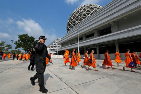 A Department of Special Investigation (DSI) officer walks with Buddhist monks from the Wat Phra Dhammakaya temple during an inspection of the temple, in Pathum Thani province, Thailand March 10, 2017. REUTERS/Chaiwat Subprasom