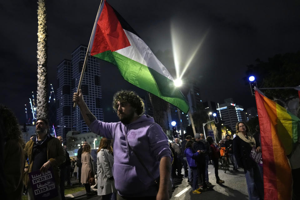 A protester holds a Palestinian flag in Tel Aviv, Israel, at a demonstration against Prime Minister Benjamin Netanyahu's far-right government, Saturday, Jan. 7, 2023. Thousands of Israelis protested plans by Netanyahu's government that opponents say threaten democracy and freedoms. (AP Photo/ Tsafrir Abayov)