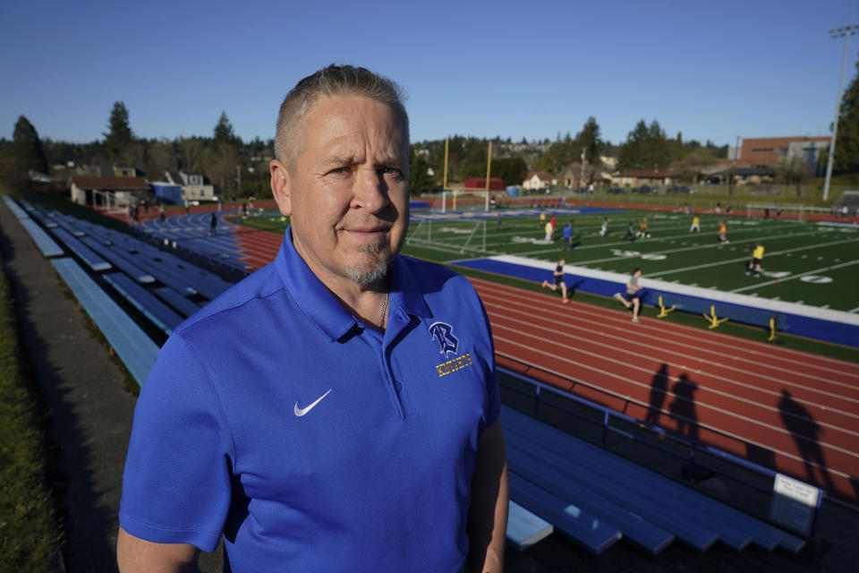 Joe Kennedy, a former assistant football coach at Bremerton High School in Bremerton, Wash., poses for a photo March 9, 2022, at the school's football field. After losing his coaching job for refusing to stop kneeling in prayer with players and spectators on the field immediately after football games, Kennedy will take his arguments before the U.S. Supreme Court on Monday, April 25, 2022, saying the Bremerton School District violated his First Amendment rights by refusing to let him continue praying at midfield after games. (AP Photo/Ted S. Warren)