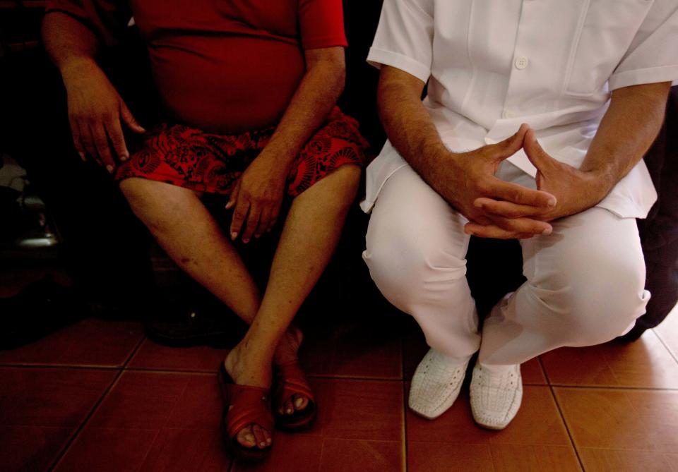 In this March 27, 2014 photo, Cuban doctor Camilo Rodriguez, right, speaks with patient Humberto Barrios as part of a post surgery visit in the Petare shanty town of Caracas, Venezuela. In exchange for the services of its doctors and other professionals, Cuba gets cut-rate Venezuelan oil that is a lifeline for Cuba's ailing economy. (AP Photo/Fernando Llano)