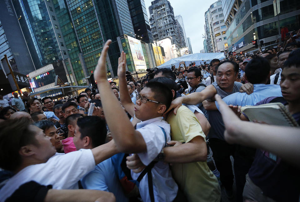 A pro-government supporter tries to grab on to a student pro-democracy activist as policeman were escorting him out of the tent, in Kowloon's crowded Mong Kok district, Friday, Oct. 3, 2014 in Hong Kong.  (AP Photo/Wong Maye-E)