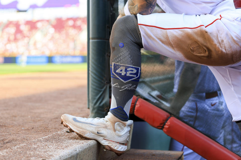 Cincinnati Reds' Jonathan India wears socks honoring Jackie Robinson as he stands on the dugout steps during the second inning of a baseball game against the Philadelphia Phillies in Cincinnati, Saturday, April 15, 2023. (AP Photo/Aaron Doster)