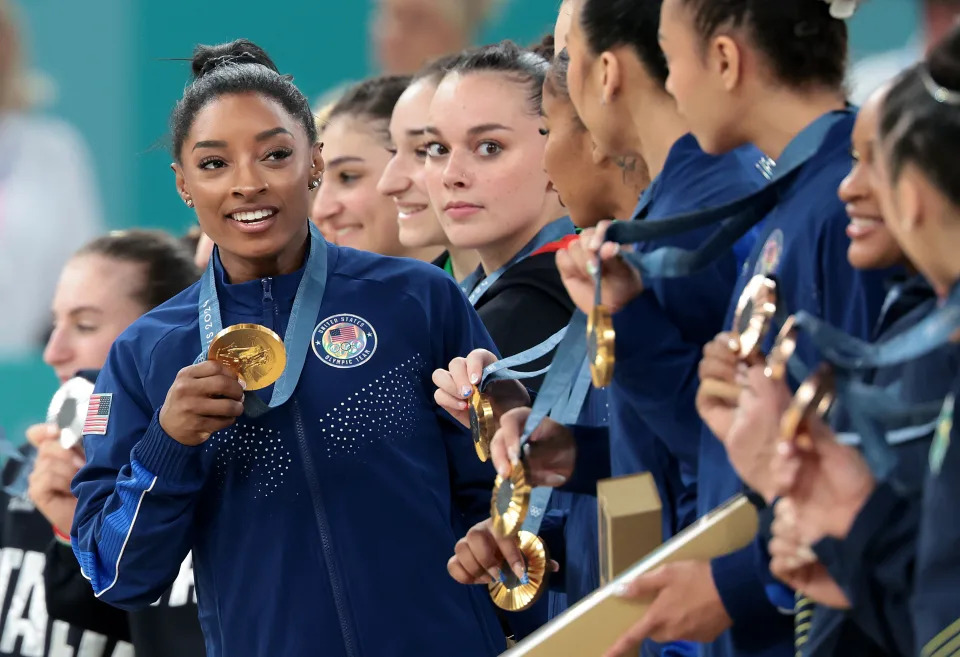 Simone Biles celebrates with a gold medal.