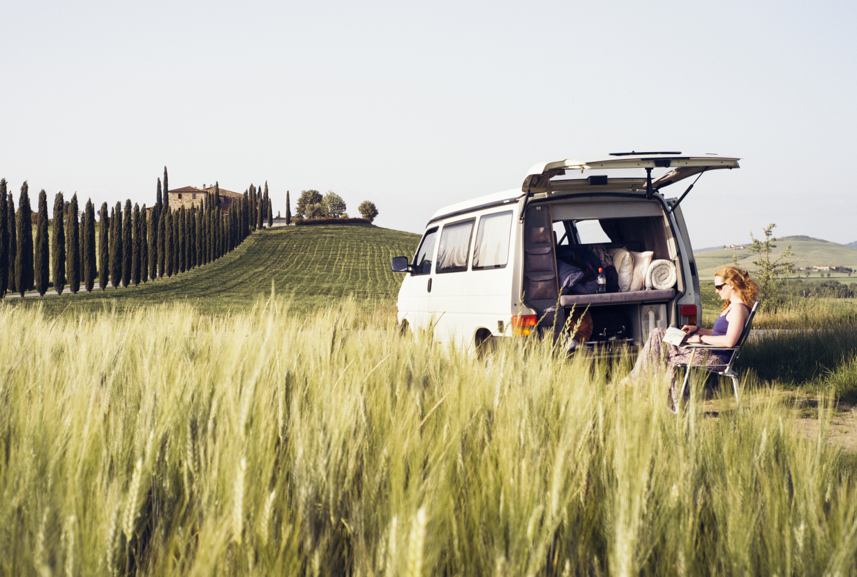 Woman Reading a Book by a RV in Tuscany, Italy