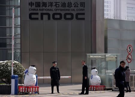 Security personnel stand next to snowmen at the entrance of China National Offshore Oil Corp (CNOOC) office tower in Beijing, March 20, 2013. REUTERS/Petar Kujundzic/File Photo