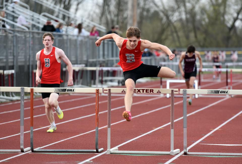 Sawyer Ulery leads Bedford teammate Alex Mapes in the hurdles during a meet against Monroe and Ann Arbor Pioneer on Monday, April 22, 2004.